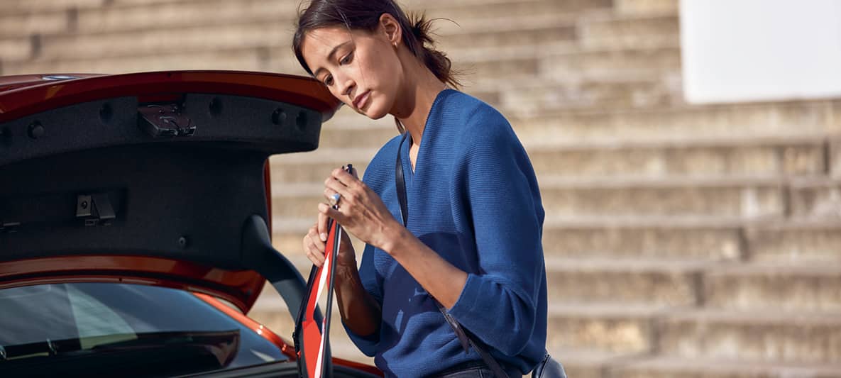 Une femme prépare son triangle de sécurité à l'arrière de sa BMW coffre ouvert Une femme prépare son triangle de sécurité à l'arrière de sa BMW coffre ouvert